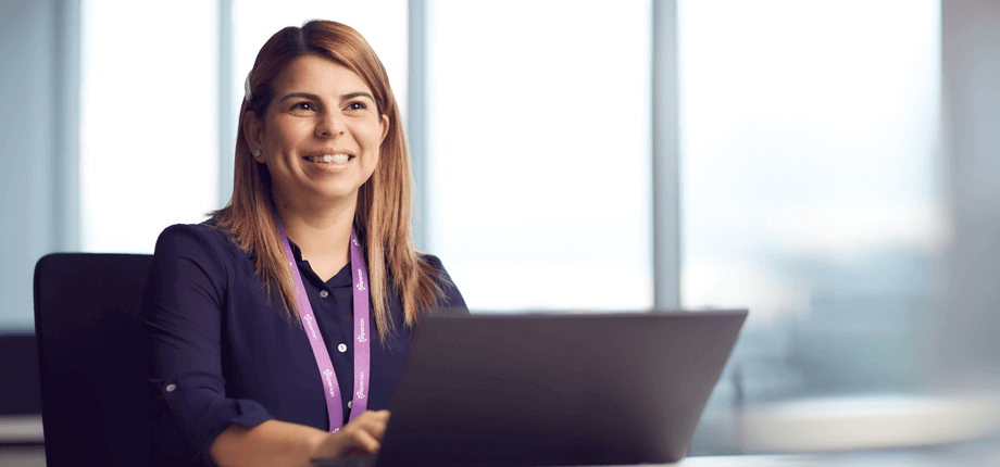 Female Experian employee sat behind her laptop in the office smiling 