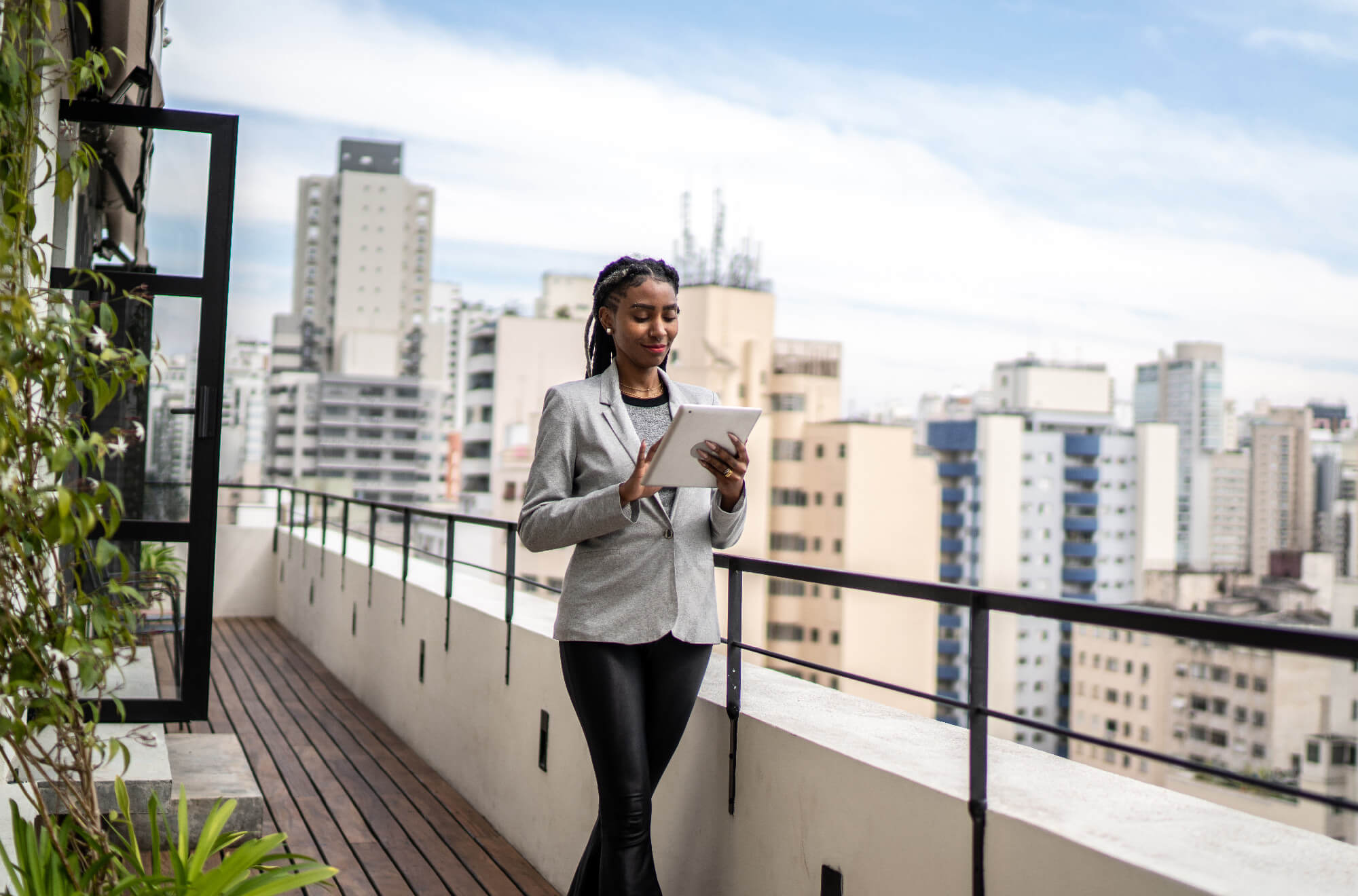 Young businesswoman using digital tablet on apartment's balcony