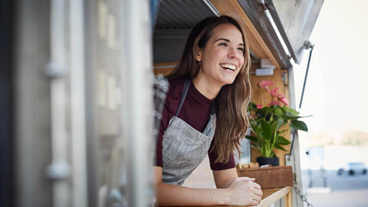 Female worker hanging out of a food truck smiling 