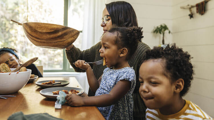 Black mother and three children having dinner together at home