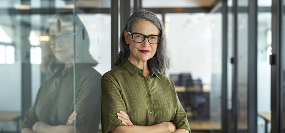 Business woman stood in an office arms folded smiling 