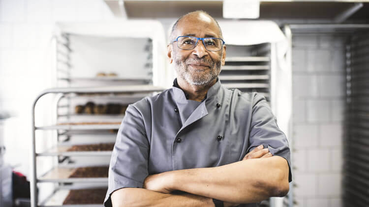 Male chef stood arms folded in his kitchen