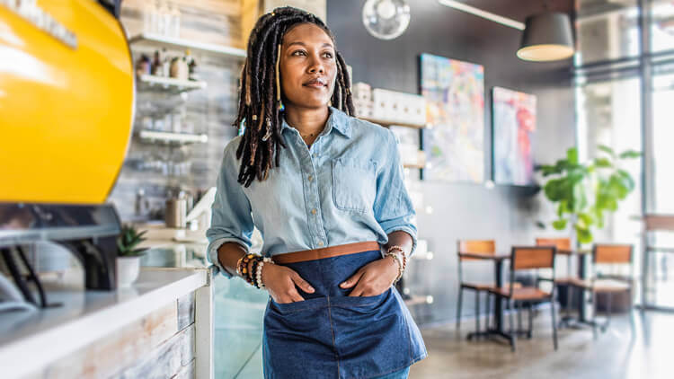 Female business owner stood in her cafe looking optimistic 