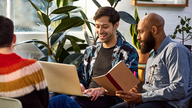 Two men in a modern office both looking at the laptop screen